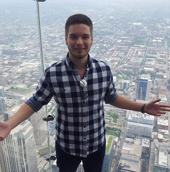 An image of a man standing with arms spread wide in front of a clear glass wall showcasing a cityscape